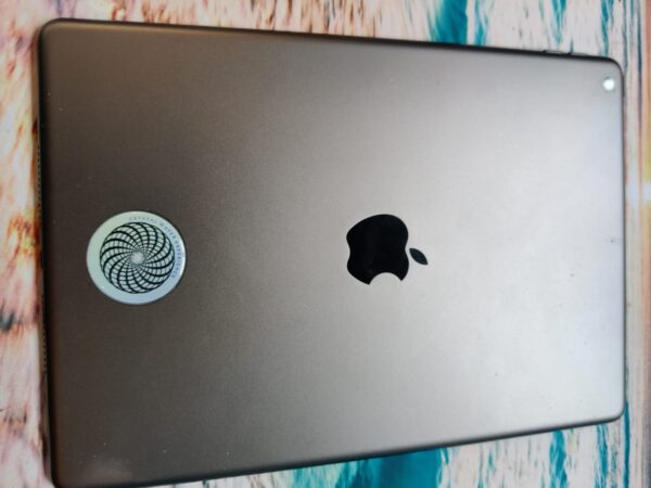 Silver iPad with Apple logo and sticker.