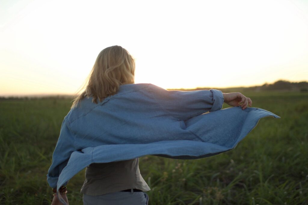 Woman in blue shirt walking in field.